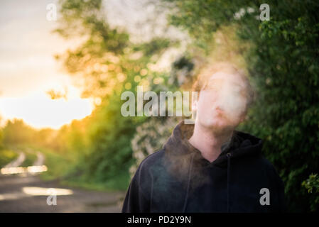 Uomo con il fumo di sigaretta per oscurare la faccia Foto Stock