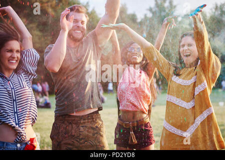 Quattro giovani amici adulti dancing e gettando gesso colorato in polvere in Holi festival Foto Stock