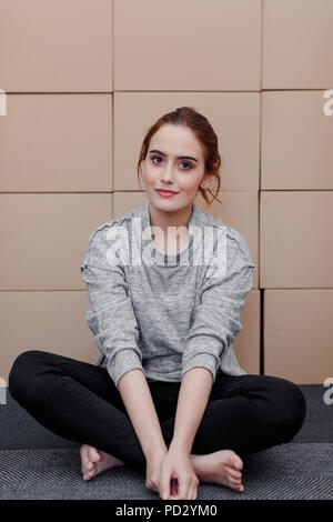 Donna seduta croce gambe, scatole di cartone in background Foto Stock