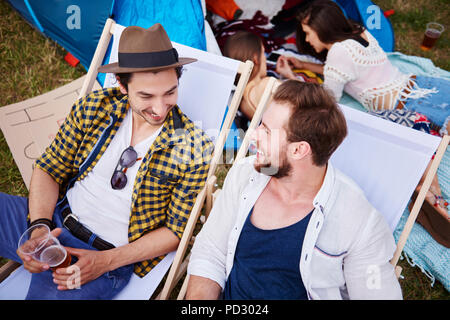 Amici seduti in sedie a sdraio in festival di musica Foto Stock