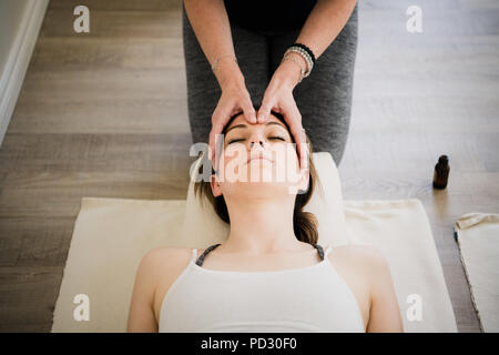 Donna godendo di massaggio della testa nel ritiro di yoga Foto Stock