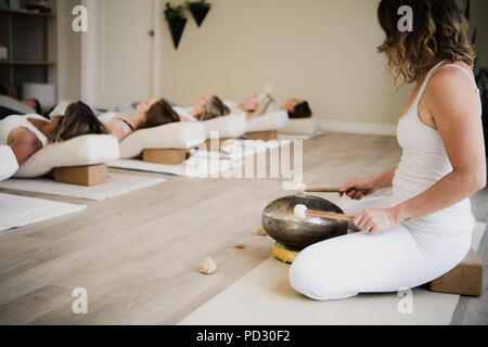 Le donne in posa di rilassamento dopo la lezione di yoga al ritiro Foto Stock