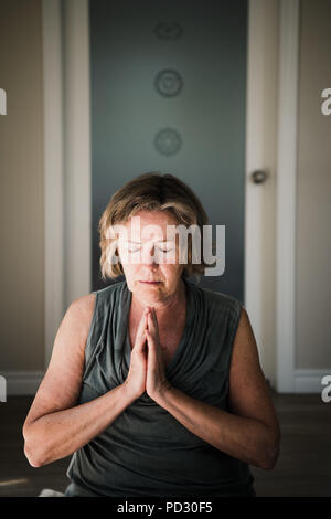 Donna con palme chiusa in postura di meditazione Foto Stock