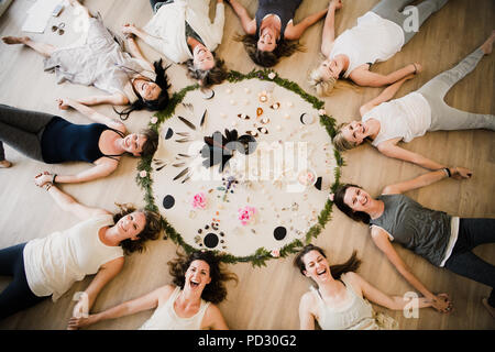 Le donne intorno al cerchio nel ritiro di yoga Foto Stock