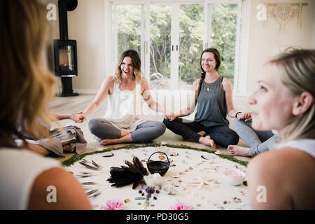 Le donne intorno al cerchio nel ritiro di yoga Foto Stock