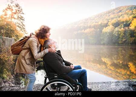 Coppia senior con la sedia a rotelle in autunno la natura. Foto Stock