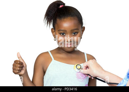 Close up ritratto di incantevole piccola ragazza africana avendo preso heartbeat.mano stetoscopio di posizionamento contro il petto.Kid facendo pollice in alto isolato su bianco Foto Stock