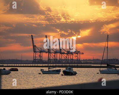 Queenborough, Kent, Regno Unito. Il 6 agosto, 2018. Regno Unito Meteo: il sole al tramonto, Queenborough, Kent. La gru di Thamesport sull'isola di Grain in distanza. Credito: James Bell/Alamy Live News Foto Stock