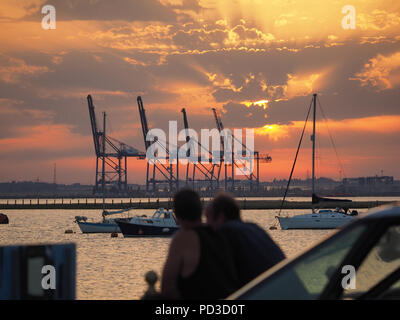 Queenborough, Kent, Regno Unito. Il 6 agosto, 2018. Regno Unito Meteo: il sole al tramonto, Queenborough, Kent. La gru di Thamesport sull'isola di Grain in distanza. Credito: James Bell/Alamy Live News Foto Stock