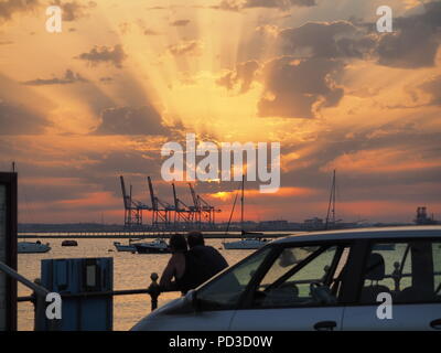Queenborough, Kent, Regno Unito. Il 6 agosto, 2018. Regno Unito Meteo: il sole al tramonto, Queenborough, Kent. La gru di Thamesport sull'isola di Grain in distanza. Credito: James Bell/Alamy Live News Foto Stock