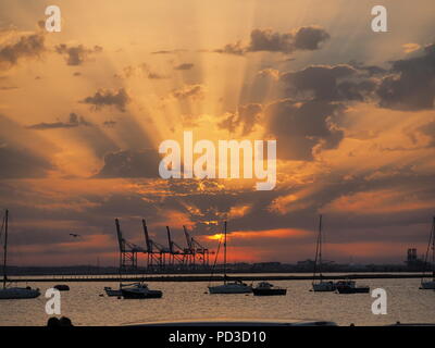 Queenborough, Kent, Regno Unito. Il 6 agosto, 2018. Regno Unito Meteo: il sole al tramonto, Queenborough, Kent. La gru di Thamesport sull'isola di Grain in distanza. Credito: James Bell/Alamy Live News Foto Stock