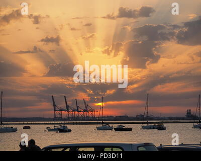 Queenborough, Kent, Regno Unito. Il 6 agosto, 2018. Regno Unito Meteo: il sole al tramonto, Queenborough, Kent. La gru di Thamesport sull'isola di Grain in distanza. Credito: James Bell/Alamy Live News Foto Stock