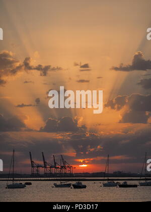 Queenborough, Kent, Regno Unito. Il 6 agosto, 2018. Regno Unito Meteo: il sole al tramonto, Queenborough, Kent. La gru di Thamesport sull'isola di Grain in distanza. Credito: James Bell/Alamy Live News Foto Stock