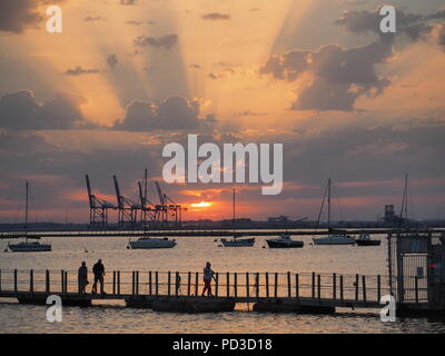 Queenborough, Kent, Regno Unito. Il 6 agosto, 2018. Regno Unito Meteo: il sole al tramonto, Queenborough, Kent. La gru di Thamesport sull'isola di Grain in distanza. Credito: James Bell/Alamy Live News Foto Stock
