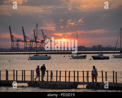 Queenborough, Kent, Regno Unito. Il 6 agosto, 2018. Regno Unito Meteo: il sole al tramonto, Queenborough, Kent. La gru di Thamesport sull'isola di Grain in distanza. Credito: James Bell/Alamy Live News Foto Stock