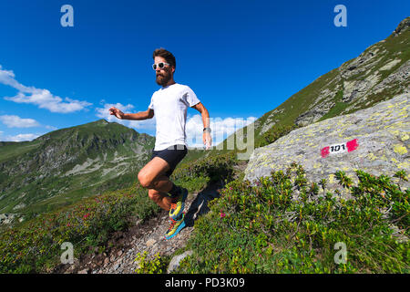 Atleta maschio praticare mountain running su un sentiero segnato dalle Alpi Orobiche. Foto Stock