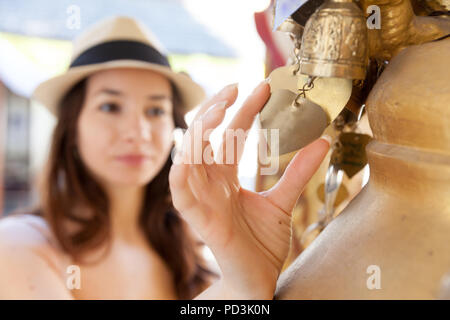 Bella giovane donna tenendo un piccolo cuore di metallo nella parte anteriore di un tempio in Thailandia. Foto Stock