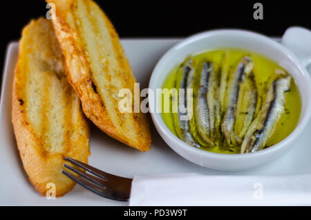 Deliziosi snack spagnolo, pesce fresco marinato in olio d'oliva, servita con crostini, tapas a base di pesce Foto Stock