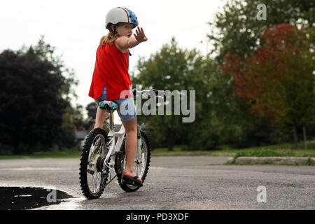 Ragazza in bicicletta fermandosi in mezzo di strada Foto Stock