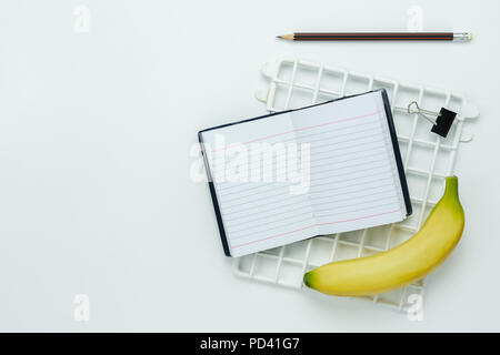 Table top visualizza immagine aerea di torna a scuola di educazione stagione di sfondo o la dieta healthcare concetto.piatto nota laici nook con banana e oggetti su Foto Stock