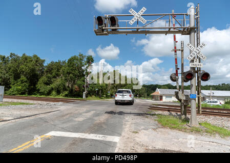 Summerfield, Florida, Stati Uniti d'America, 2018. I segnali ferroviari e la via che passa attraverso il North Florida campagna. Auto che attraversa la giunzione. Foto Stock