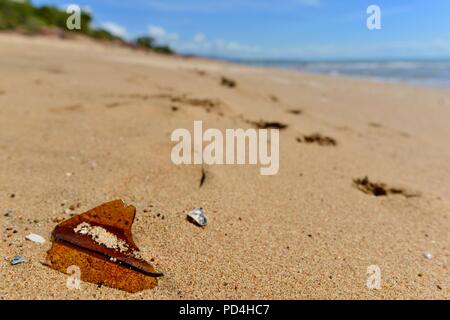 Orme nella sabbia vicino al vetro rotto, Toomulla QLD, Australia Foto Stock