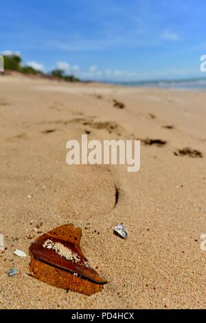 Orme nella sabbia vicino al vetro rotto, Toomulla QLD, Australia Foto Stock