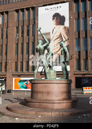 Stili di vita contrapposti nel centro di Helsinki in Finlandia, la scultura di ironworkers industriale in bronzo adagiato contro un gigant board la promozione del marchio di sabbia Foto Stock