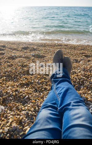 Gli uomini con i piedi sul sfondo della spiaggia del mare. Una vacanza in un resort sul mare Foto Stock