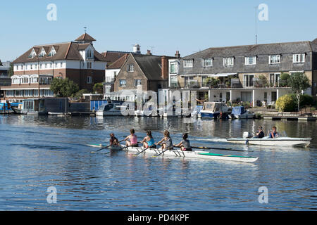 Femmina team a remi con il motoscafo escort sul fiume Tamigi vicino a Kingston, con Hampton Wick in background Foto Stock