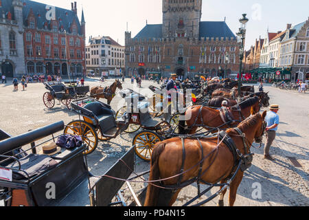Cavallo e trappole schierate in Markt Square vicino Campanile Bruges Bruges, Belgio. Il cavallo e i trap vengono utilizzati per prendere i turisti sulle visite guidate della città Foto Stock