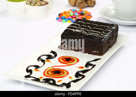 Square succosa spugna di cioccolato torta umida con la salsa in stampo e caffè Foto Stock