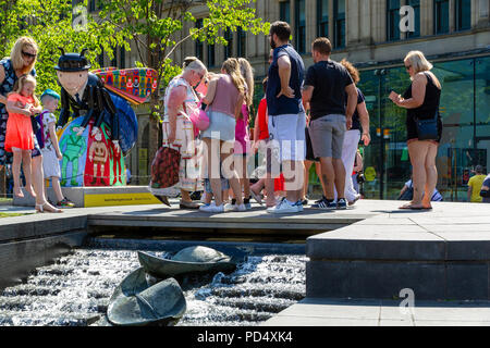 La folla di gente radunata attorno a un APE in Cattedrale Giardini a Manchester Bee Trail Foto Stock