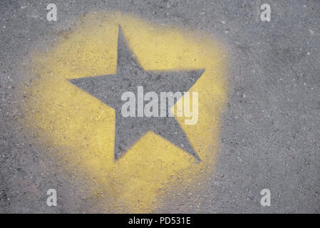 La stella gialla è dipinta su GRIGIO ASFALTO. Foto Stock