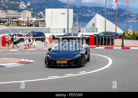 McLaren nero 570S diving sul Circuito de Monaco e l'ingresso del Fairmont tornante di circuito di Strada di Monte Carlo Foto Stock