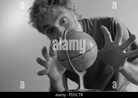 Fuori fuoco uomo dietro vintage globo terrestre Foto Stock