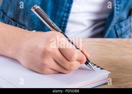 Bambino la mano che tiene la penna. Il bambino a scrivere lettere in un notebook. Foto Stock