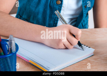 Bambino la mano che tiene la penna. Il bambino a scrivere lettere in un notebook. Foto Stock