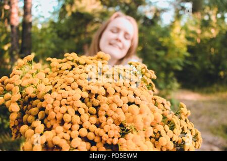 Un giovane, bella e felice ragazza riceve un enorme bougette di fiori selvatici giallo come un presente. Sorride ed è molto felice di questo dono. Foto Stock