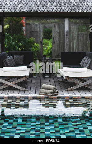 Vista della piscina con set di asciugamani puliti e due chaise-longue Foto Stock