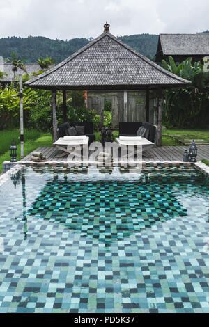 Vista della piscina con set di asciugamani puliti e due chaise-longue Foto Stock