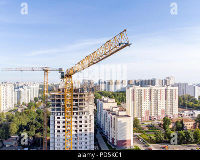 Giallo alta gru a torre multipiano vicino edificio di appartamenti in costruzione. la fotografia aerea Foto Stock