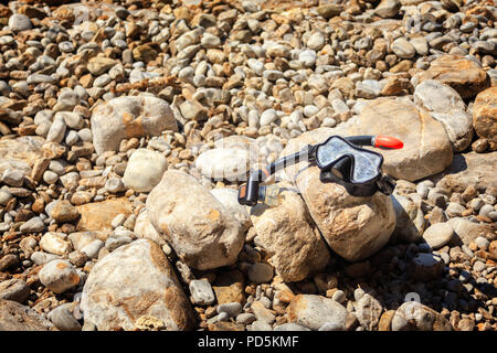 La maschera e il tubo per il nuoto si trova sulle pietre Foto Stock