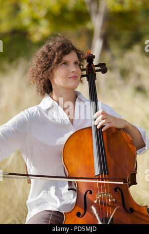 Donna che gioca il violoncello tra i campi Foto Stock