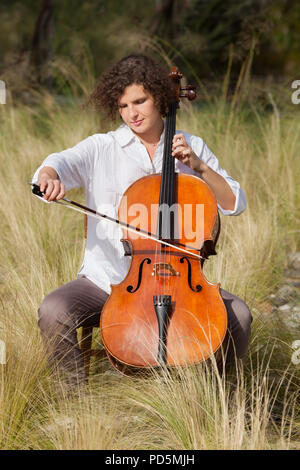 Donna che gioca il violoncello tra i campi Foto Stock