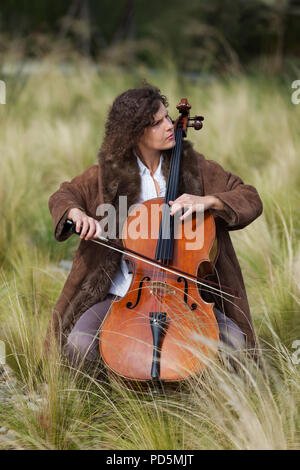 Donna che gioca il violoncello tra i campi Foto Stock