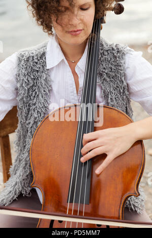 Donna che gioca il violoncello al mare Foto Stock