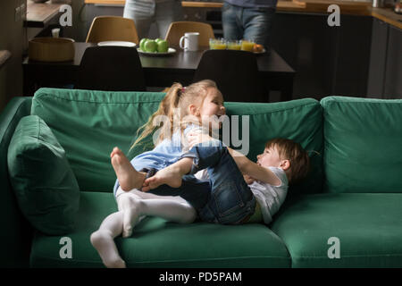 Kids sorella e fratello di ridere solletico sul divano giocando togeth Foto Stock