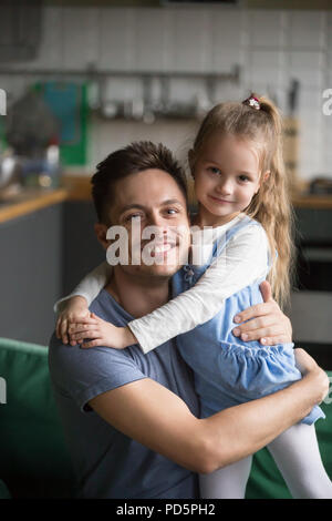 Ritratto verticale di capretto felice figlia che abbraccia il padre a casa Foto Stock