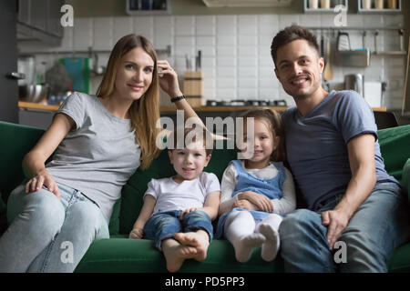 Ritratto di genitori felici con graziosi bambini seduti sul divano Foto Stock